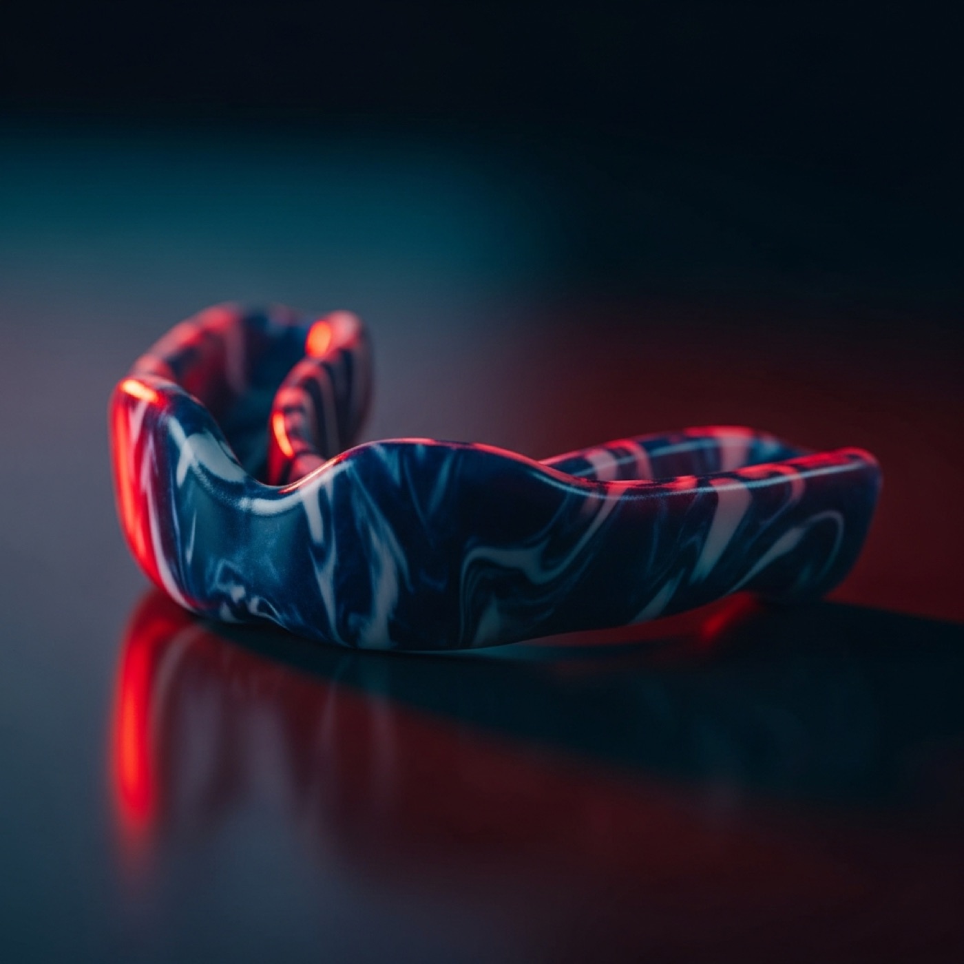 Navy and white marbled custom mouthguard in a dark studio